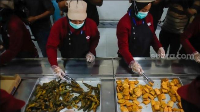 An officer prepares meals for the Free Nutritious Meals (MBG) programme, managed by Jimmy Hantu, at the SPPG Mutiara Keraton Solo in Tamansari, Bogor, Tuesday (16 December 2025). [Suara.com/Alfian Winanto]