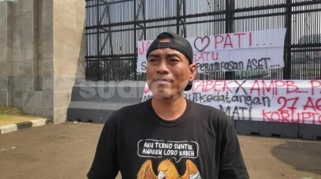 Supriyono, also known as Botok, an activist with the Pati Bersatu Community Alliance (AMPB), stands outside the Indonesian Parliament building in Jakarta on Friday (21 August 2026). [Suara.com/Bagaskara]
